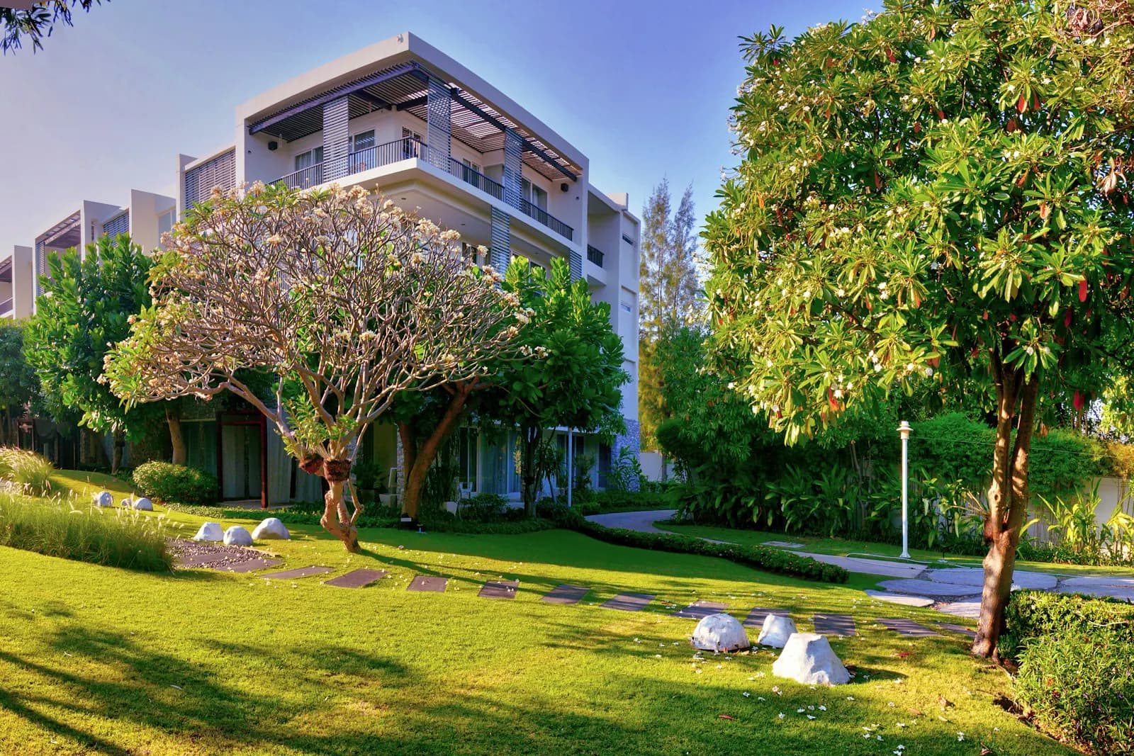 Landscaped apartment community with balconied units set behind mature garden trees