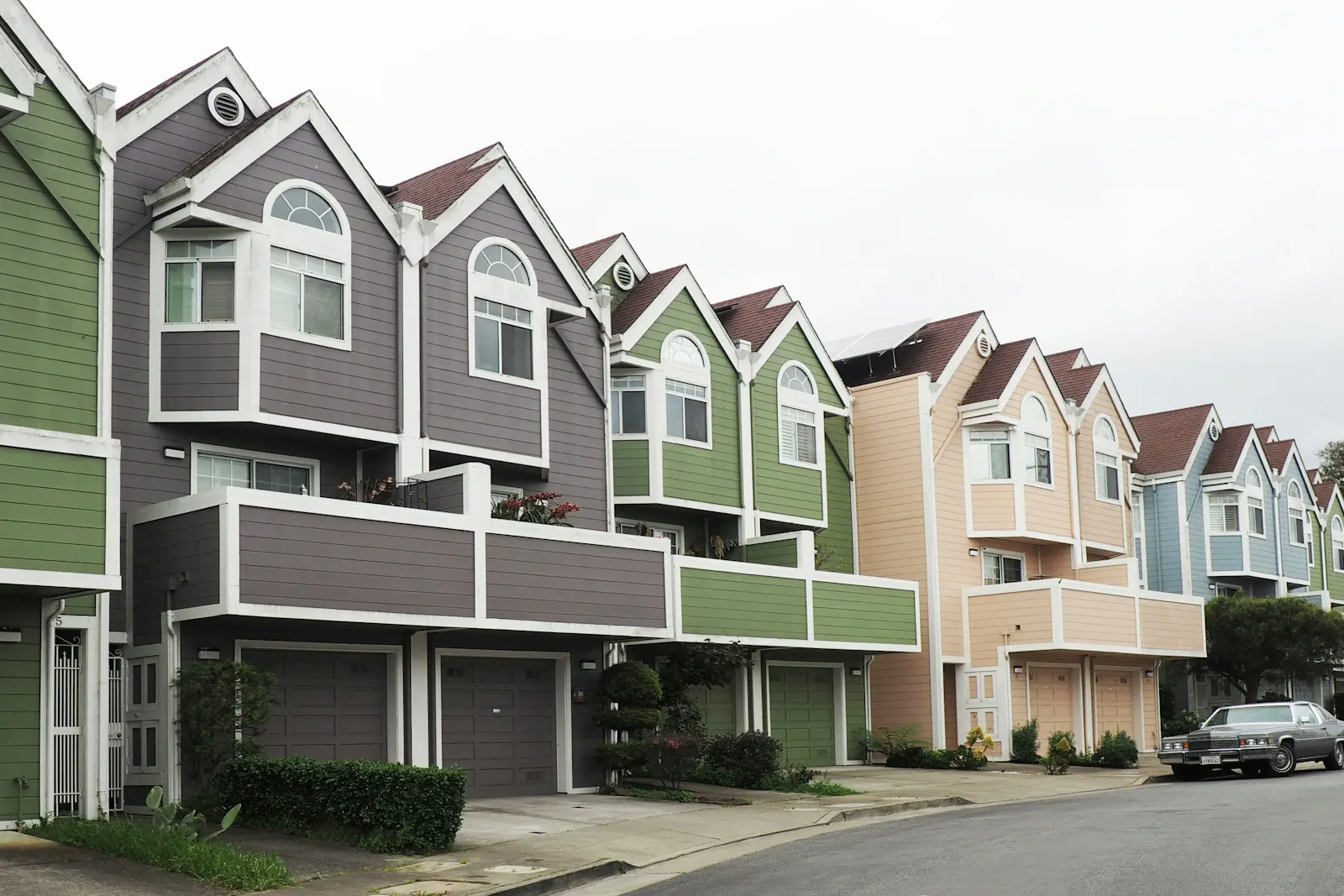 Row of three-story townhomes in varied siding colors, each with its own garage